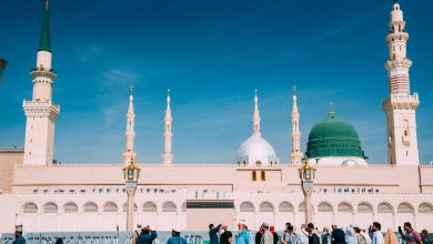 Crowds gather outside the majestic Prophet's Mosque on a sunny day in Medina, Saudi Arabia.