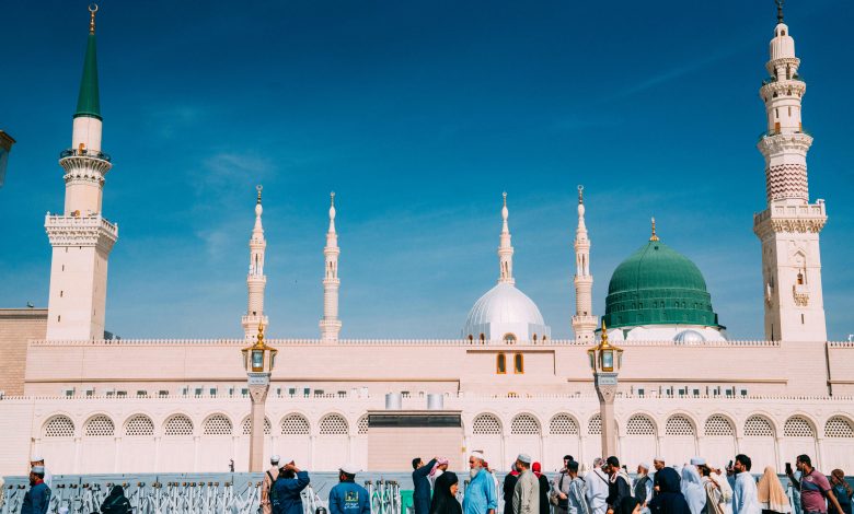 Crowds gather outside the majestic Prophet's Mosque on a sunny day in Medina, Saudi Arabia.