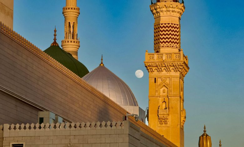 Stunning shot of the Prophet's Mosque minarets in Medina during dusk with a clear view of the moon.